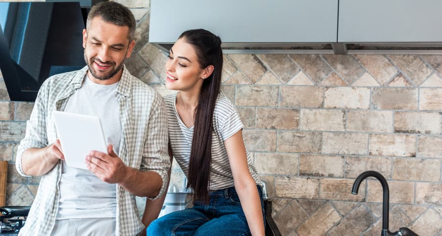 Young couple using a tablet together in the kitchen to control smart home